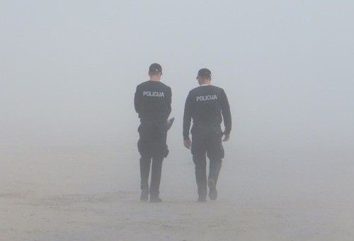 2 policiers de dos marchant dans la brume